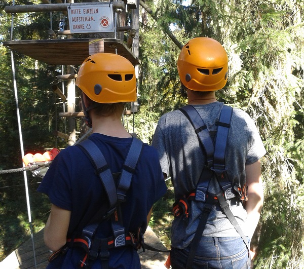 Zwei Personen mit Helm schauen auf den Kletterpark