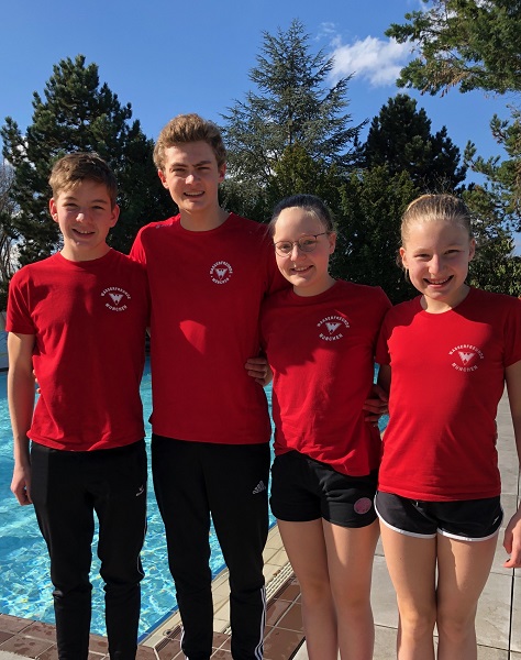 Vier Schwimmer im Freien vor einem Pool