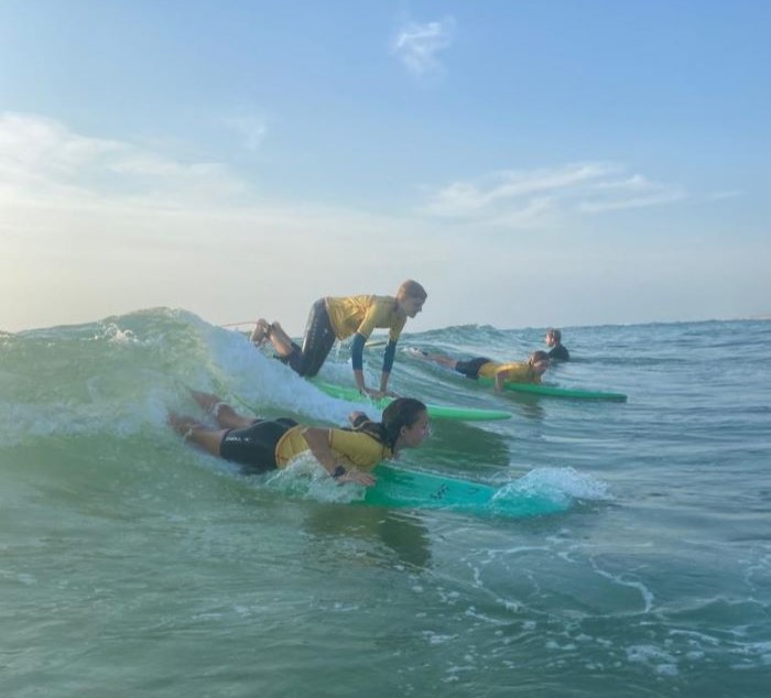 3 Kinder mit Surfbrettern auf einer Welle